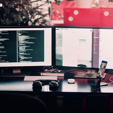 two black computer monitors on black table