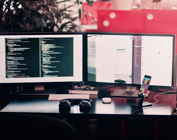 two black computer monitors on black table