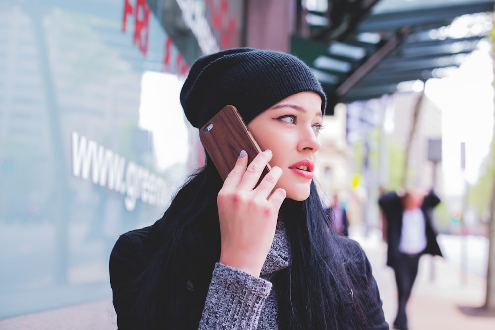 woman wearing beanie with smartphone on ear