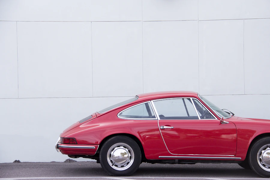 Red classic sports coupe photographed in profile against a plain backdrop