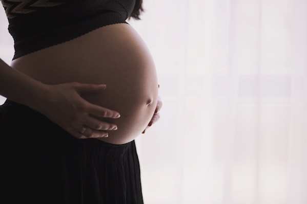 Close-up of a pregnant woman carefully stretching during a Pilates session in a cozy living room.