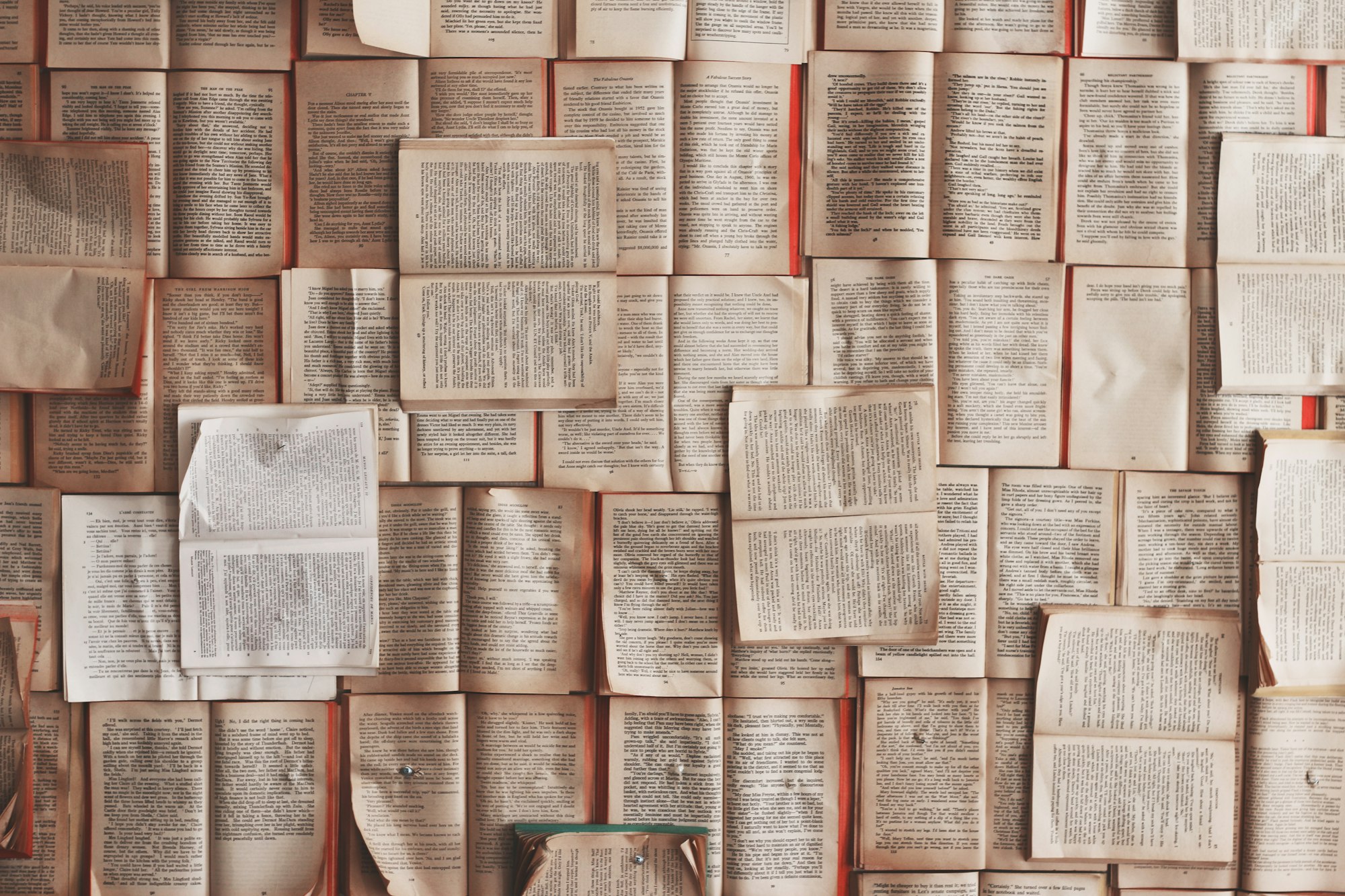 A bunch of open books are laid out across a table.