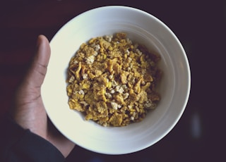 person holding white ceramic bowl filled with cereal