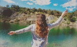 woman in gray top standing near body of water