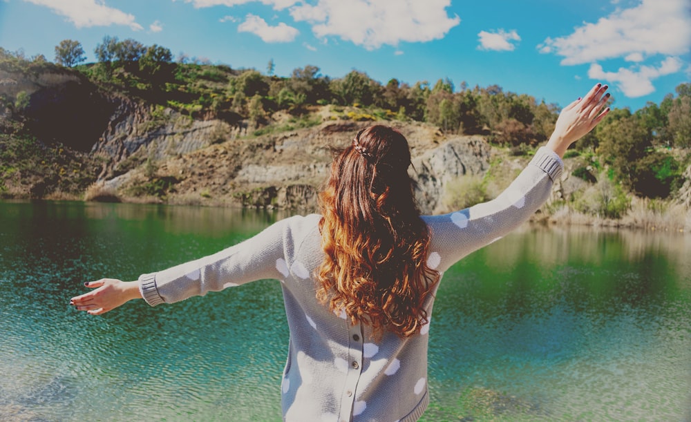 woman in gray top standing near body of water