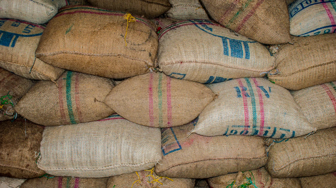 Printed jute sacks of green coffee stacked in a warehouse in Quindío, Colombia.