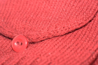 Close-up of cherry’s handcrafted stitching detail on a vibrant red hoodie.