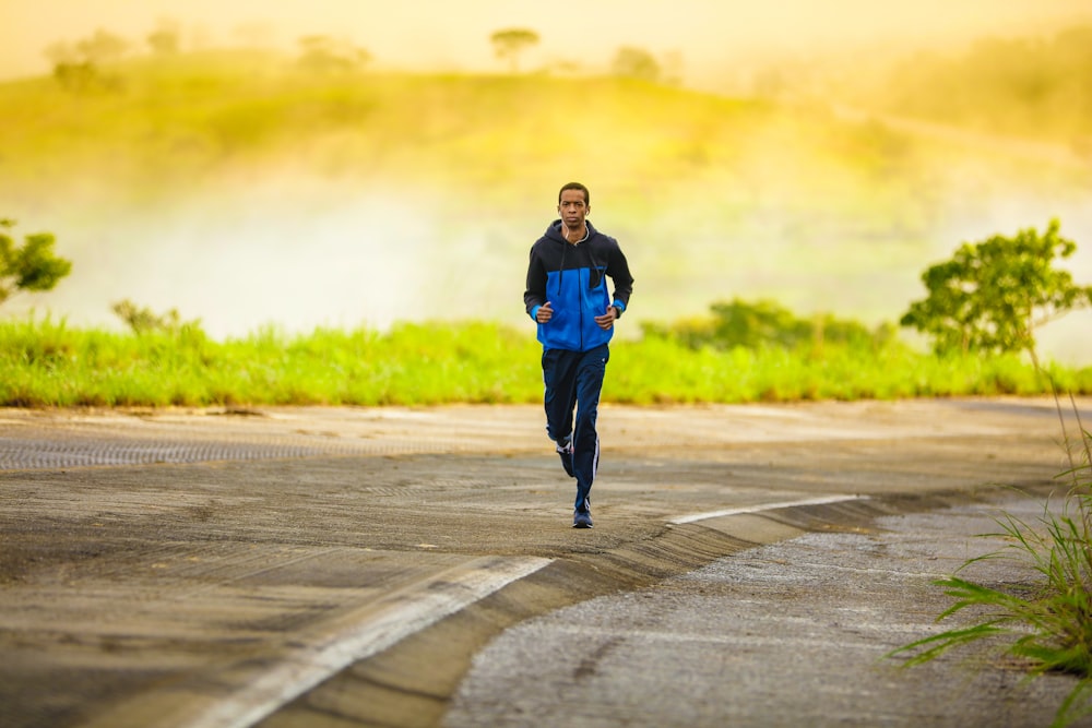 uomo in tuta da ginnastica che fa jogging sulla strada di cemento