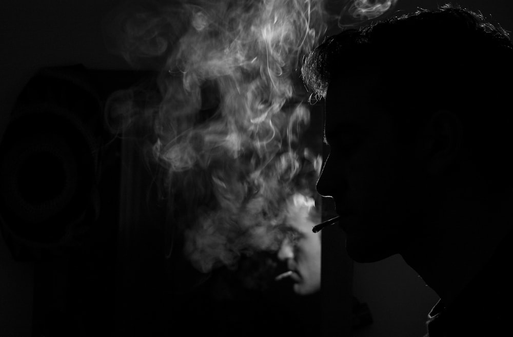 grayscale photography of man smoking cigarette