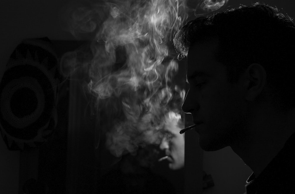 grayscale photography of man smoking cigarette