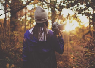 woman in forest holding DSLR camera during golden hour