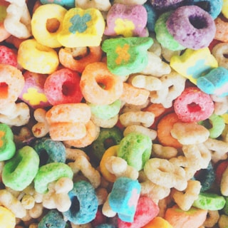 Close-up of vibrant, colorful high-protein cereal spilling from a bright yellow bowl.