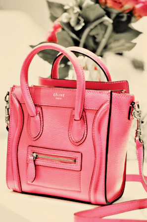 Blush pink sling bag hanging on a modern chair against a soft beige background.