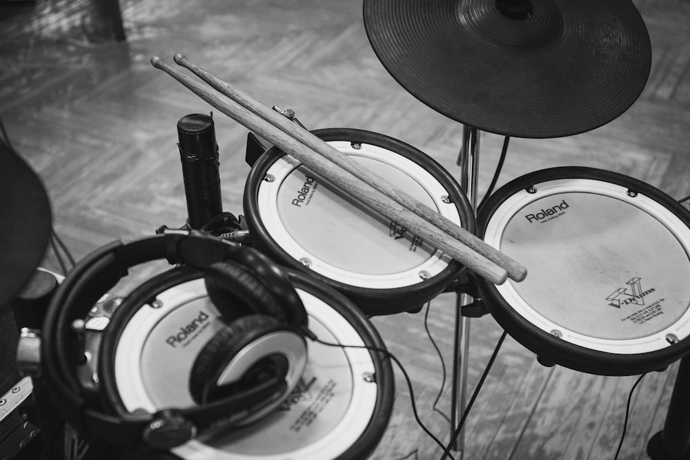 grayscale photo of drumsticks on electric drum kit