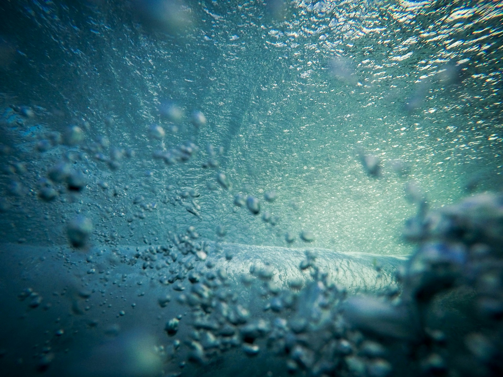 An underwater scene filled with bubbles and waves, with light filtering through the water, creating a shimmering effect.