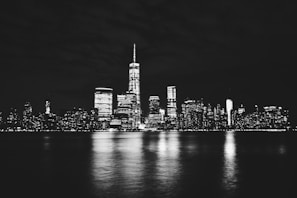 Nighttime view of New York skyscrapers with glowing lights in black and white
