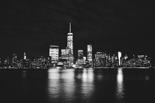 A stylish black and white photo of a city skyline at night with subtle glowing lights highlighting buildings.