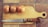 A wooden cutting board placed on a tiled surface with three whole onions lined up on top. A knife with a wooden handle is resting next to the onions.