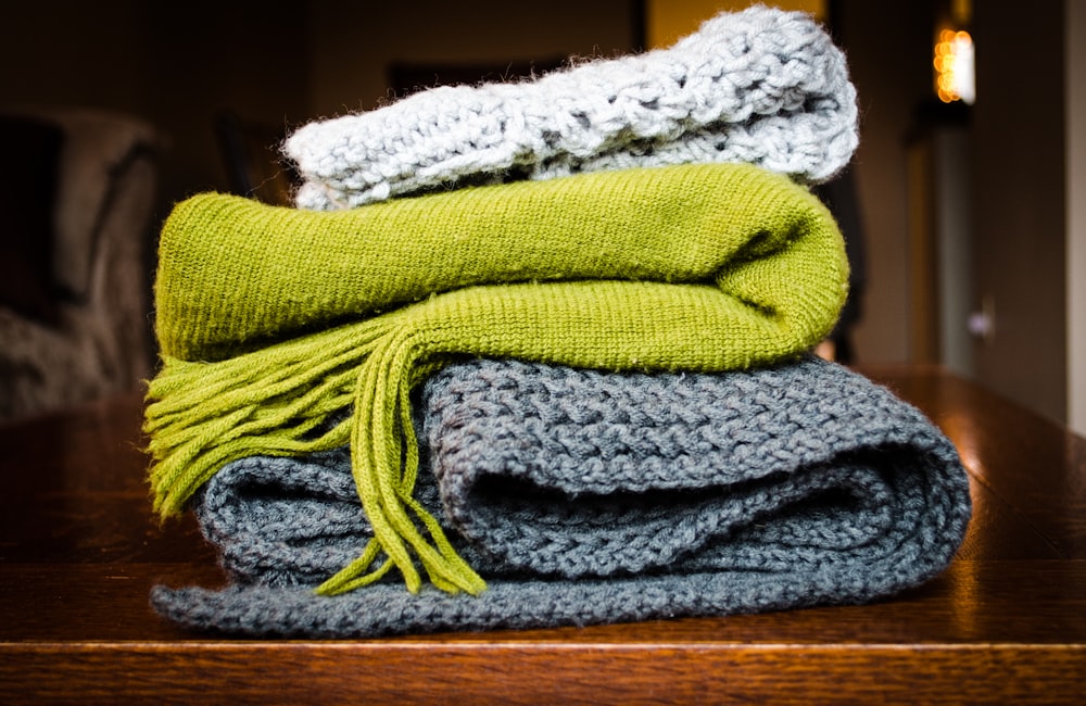 tres bufandas grises, verdes y blancas en la parte superior de la mesa
