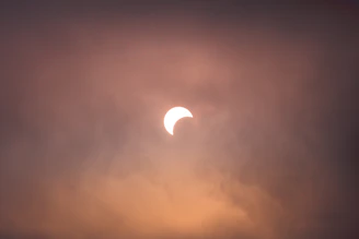 Close-up of hands holding eclipse glasses with the sun partially covered in the background.