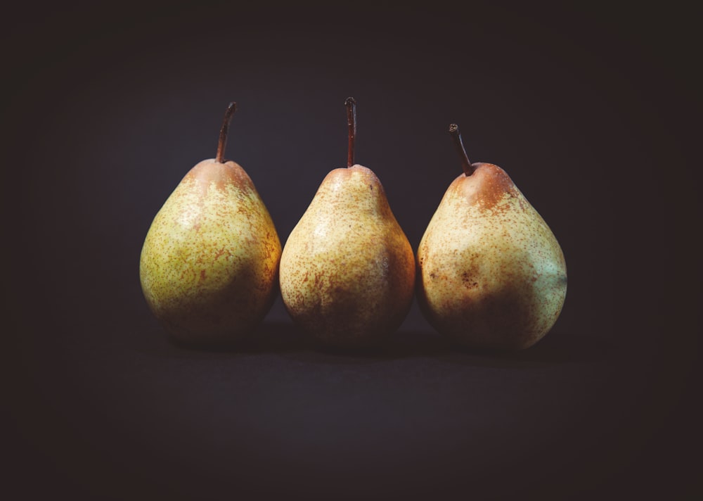 three pears on black surface