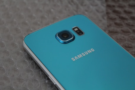 A blue Samsung smartphone resting on bubble wrap, showcasing its rear camera and metallic blue finish.
