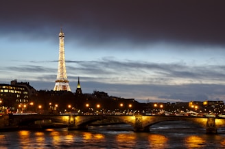 Twinkling lights over a charming Parisian bridge at dusk.