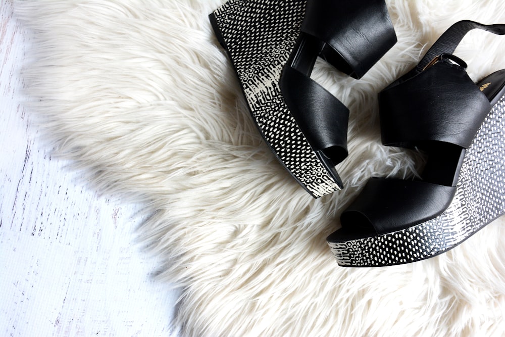 Paar schwarz-graue Damen-Wedges auf weißem Pelztextil