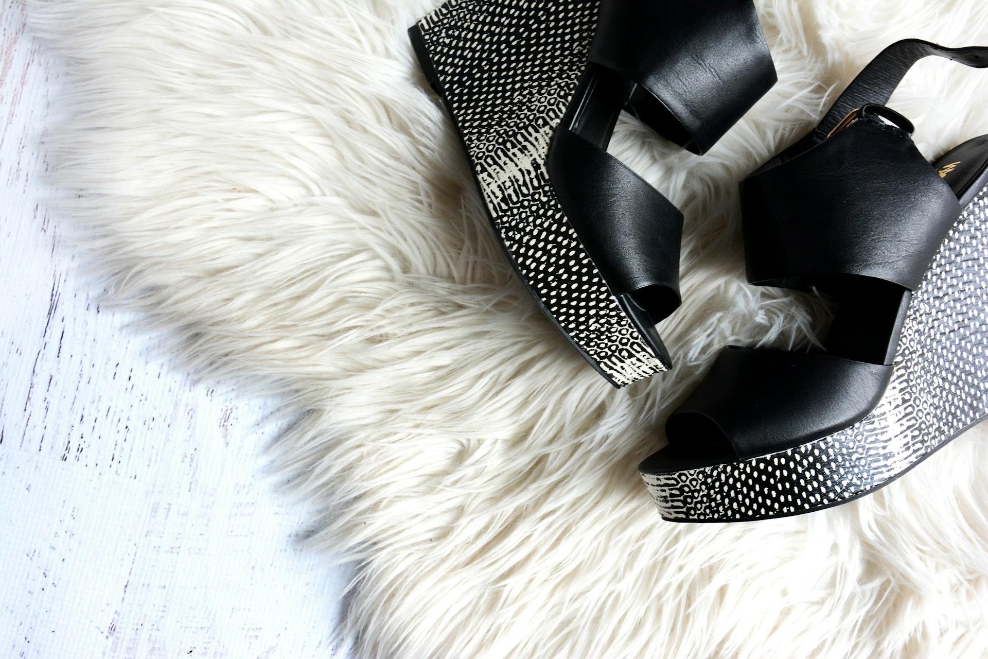 pair of women's black-and-gray wedges on white fur textile