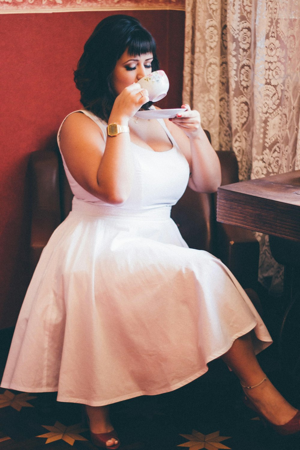 A woman sipping on a cup of tea.