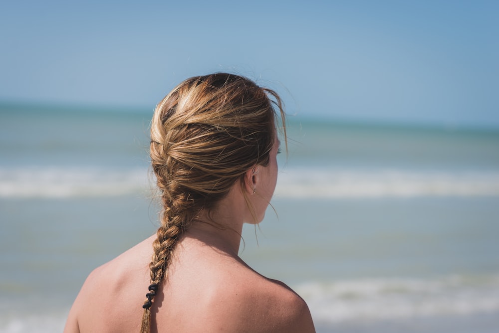 바다 근처에서 땋은 머리를 가진 여자의 뒷모습 사진