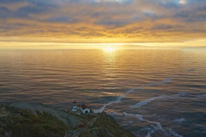Sunset view over the Atlantic Ocean from a rocky cliff near a lighthouse