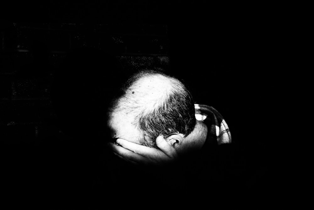 a black and white photo of a man with his head in his hands