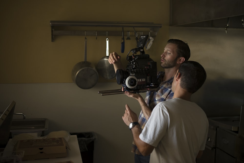 two men fixing camera inside kitchen