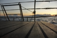A freshly varnished wooden deck gleaming under soft morning light on a sailboat.