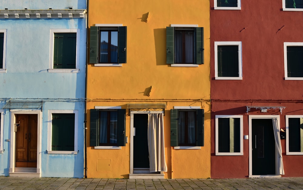 Minimalistische Fotografie von offenen Türen und Fenstern farbiger Gebäude