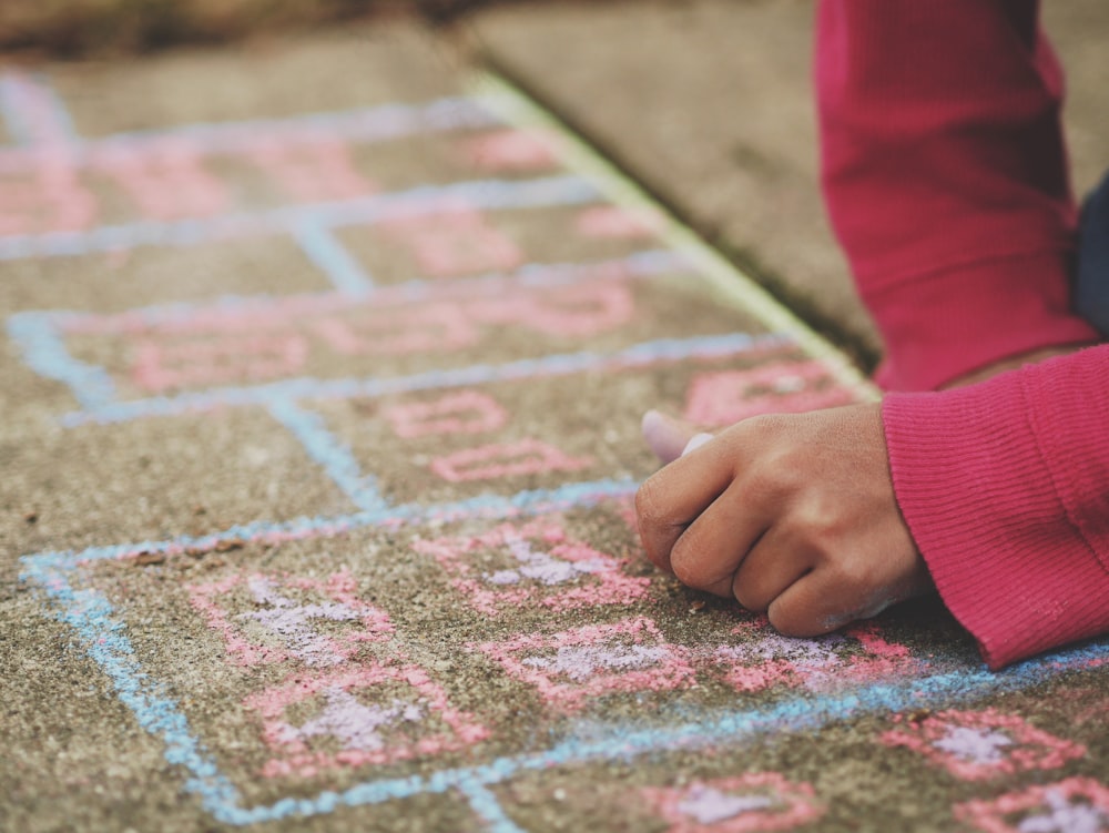 person holding chalk lying on concrete surface