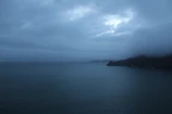 A wide shot of the ocean horizon under a cloudy sky with soft shadows.