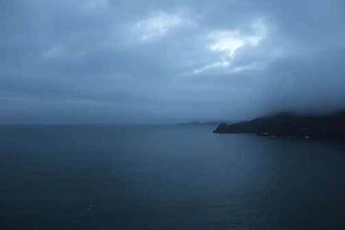 A wide shot of the ocean horizon under a cloudy sky with soft shadows.