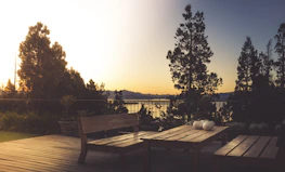 A beautifully designed wooden deck next to a sparkling ornamental lake at sunset.