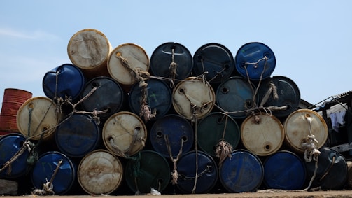 Stacks of fuel barrels ready for shipment at a Kenyan depot under a bright blue sky.