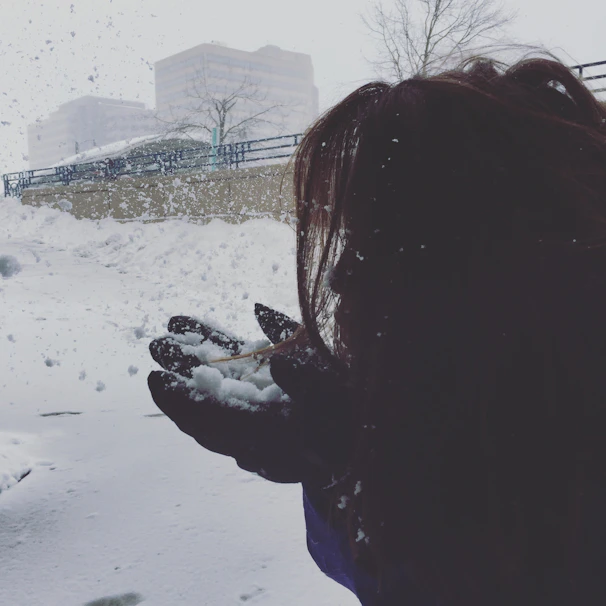Hands exchanging a donation envelope with a backdrop of snowy city streets at dusk.