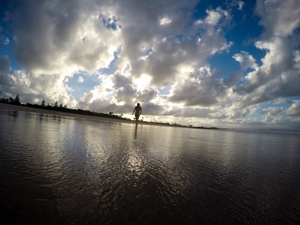 Eine Frau, die auf dem Wasser an einem Strand spazieren geht.