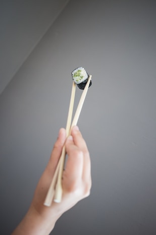 A hand holding a piece of sushi ready to be dipped in soy sauce.