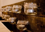 A DIY project in progress: painted mason jars turned into charming candle holders on a rustic table.