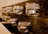 Rows of small glass mason jars are attached to a rustic wooden plank. Each jar contains a tealight candle and is adorned with twine around the rim, exuding a warm and cozy atmosphere.