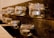 Rows of small glass mason jars are attached to a rustic wooden plank. Each jar contains a tealight candle and is adorned with twine around the rim, exuding a warm and cozy atmosphere.