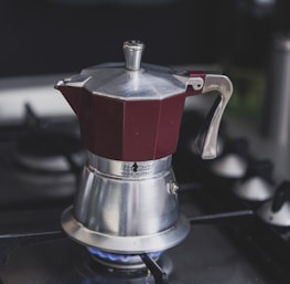maroon and silver-colored kettle on stove