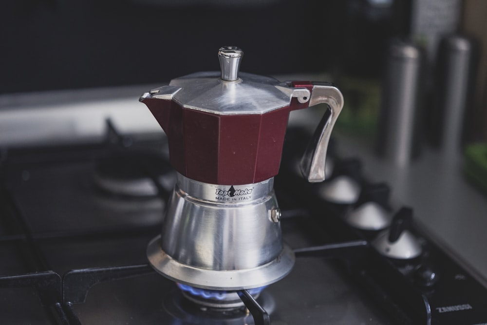 maroon and silver-colored kettle on stove