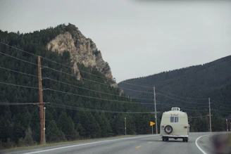 A winding mountain road at sunrise, symbolizing freedom and adventure with a camper van.